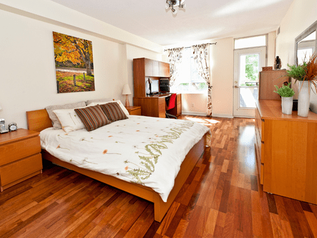 A bedroom with hardwood floors and a large bed.