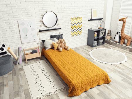 A bed room with a yellow bedspread and a rug