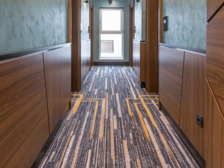 A hallway with many different colored carpet and wood cabinets.