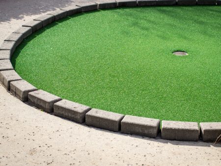 A green golf course with cement curbs around it.