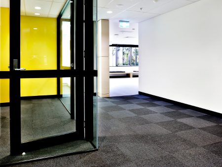 A hallway with a glass door and yellow wall.