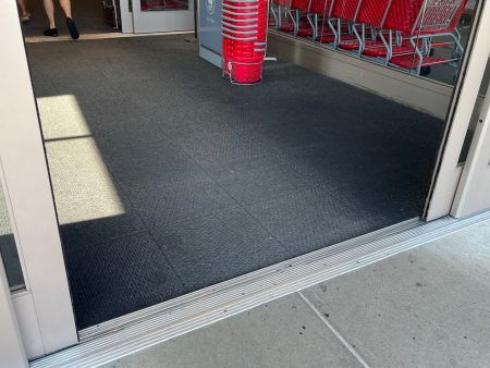 A black mat is on the ground outside of a building.